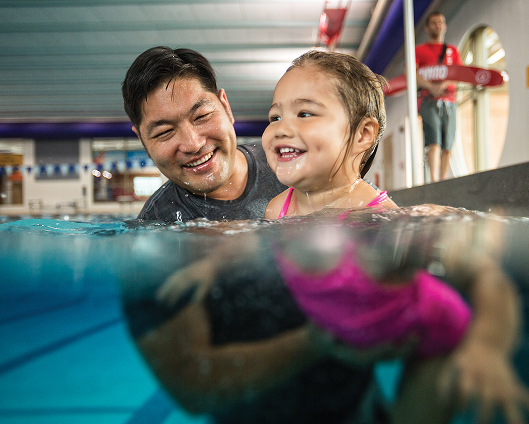 An Adult male helping a youth learning how to swim.