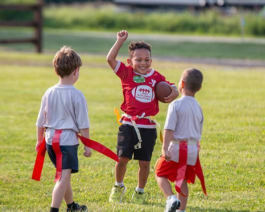 A youth enjoying his touchdown while playing flag football in the YMCA Bitty Sport program.