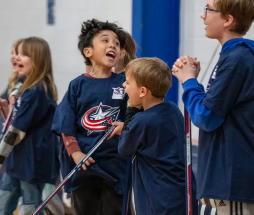 kids lined up with hockey sticks, shouting with smiles